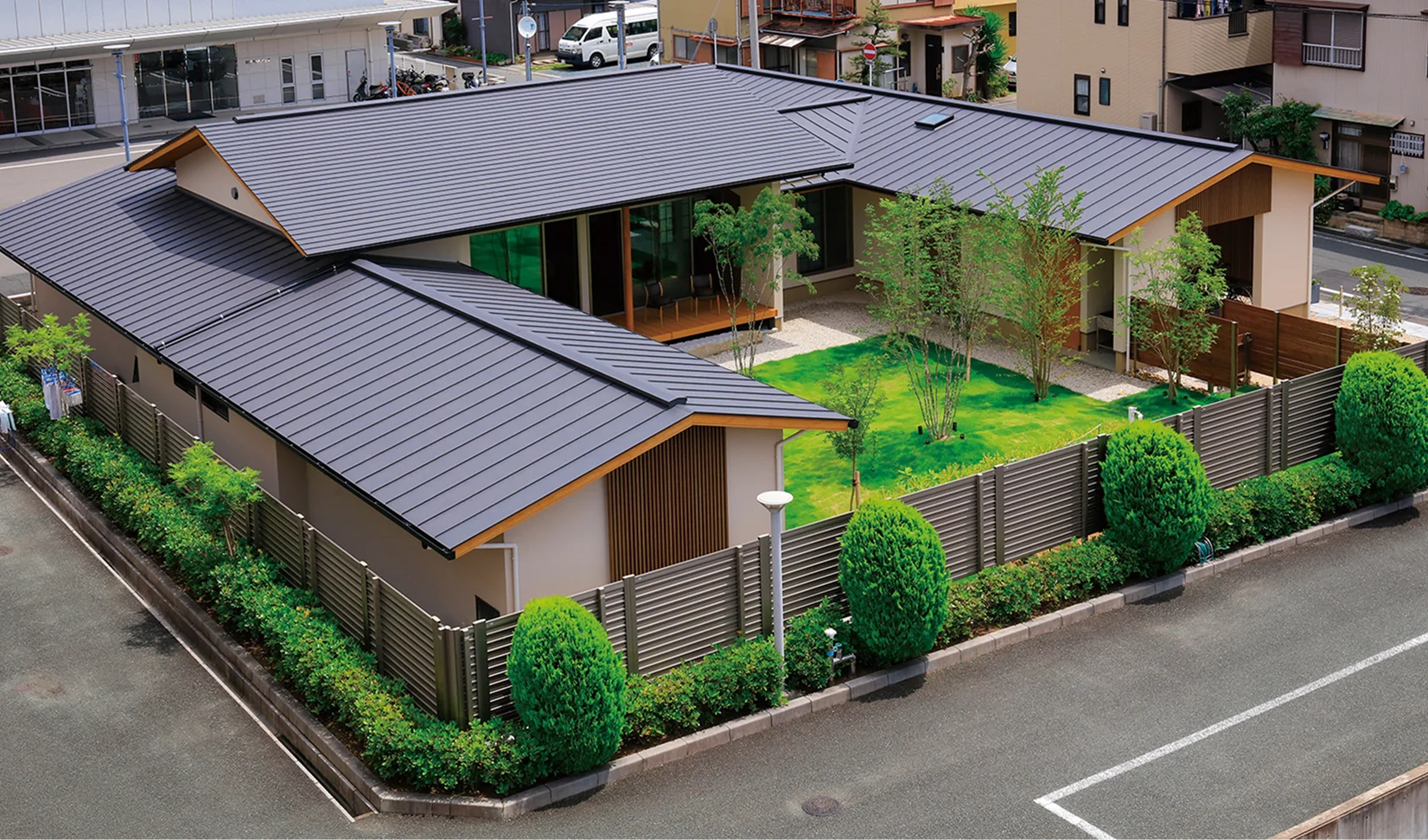 緑の庭と生け垣に囲まれた平屋の住宅を俯瞰した外観
