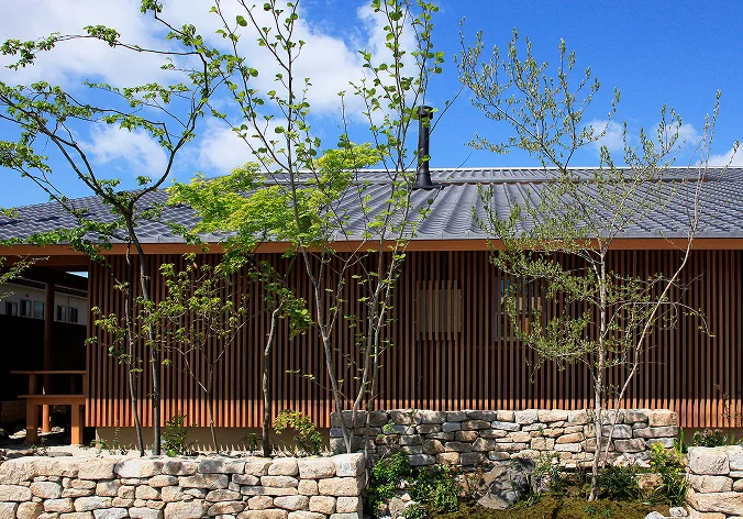 瓦屋根と縦格子の外壁、石垣のある木造建物