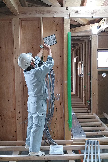 木造建築現場で配線工事を行う作業員